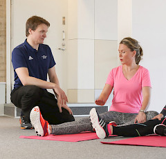 Ohjaaja keskustelee kyykyssä venyttelevän ohjattavan kanssa