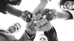 Joukko aikuisia lyö nyrkkinsä yhteen yhteistyön merkiksi