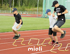 Kolme nuorta urheilijaa juoksuradalla hyppäämässä aitojen yli