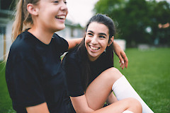 Kaksi nuorta istumassa nurmikentällä