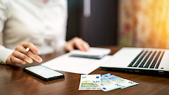 Pöydällä läppäri, rahaa, kännykkä